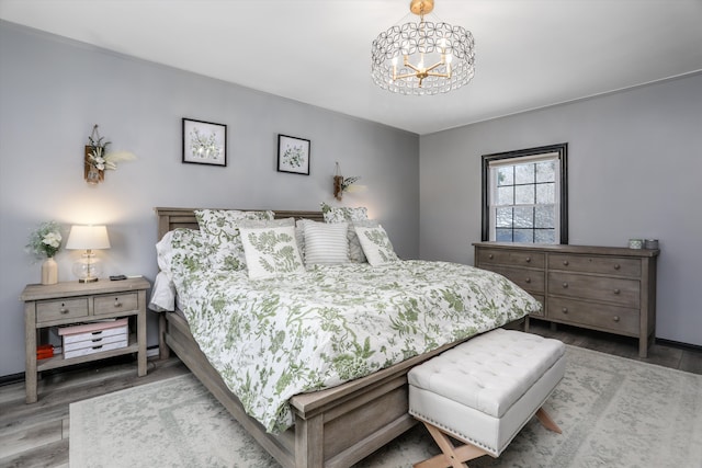 bedroom with an inviting chandelier, baseboards, and wood finished floors