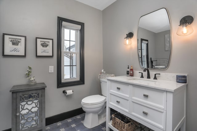 bathroom with baseboards, vanity, and toilet