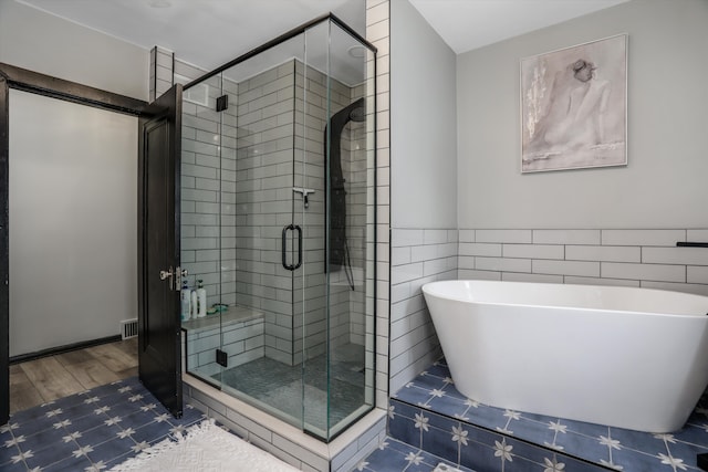 full bath with wood finished floors, a freestanding tub, and a shower stall