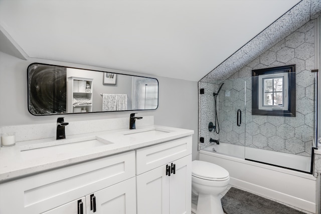 bathroom with double vanity, toilet, combined bath / shower with glass door, and a sink