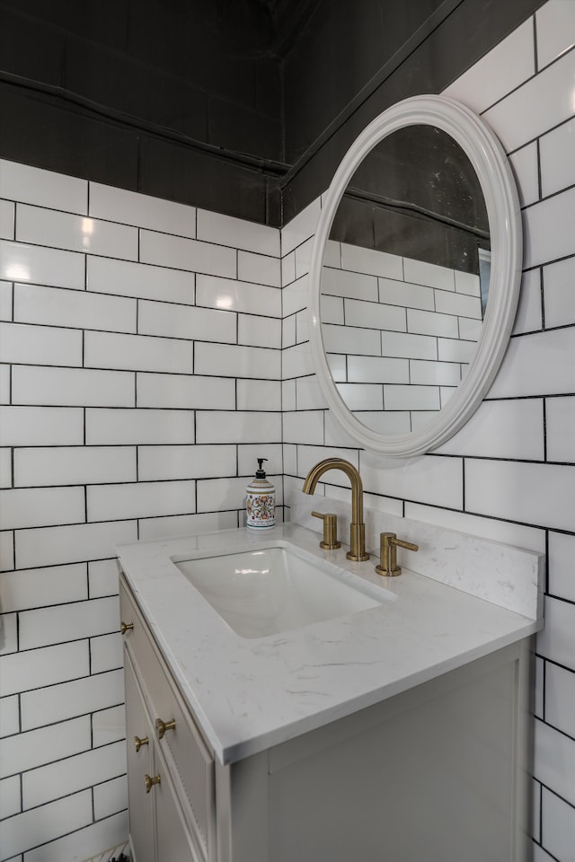 kitchen with light stone counters, white cabinetry, a sink, and backsplash