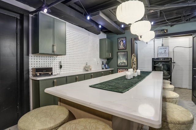 kitchen with black oven, a breakfast bar, decorative light fixtures, and green cabinetry