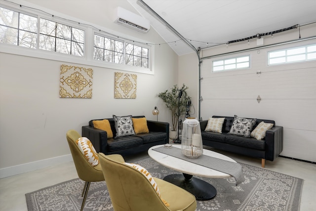 living area featuring finished concrete flooring, a wall mounted AC, a garage, and baseboards