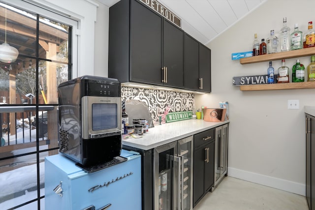 kitchen with beverage cooler, baseboards, lofted ceiling, dark cabinetry, and open shelves