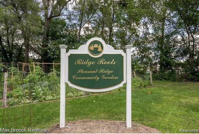 community / neighborhood sign featuring fence and a lawn