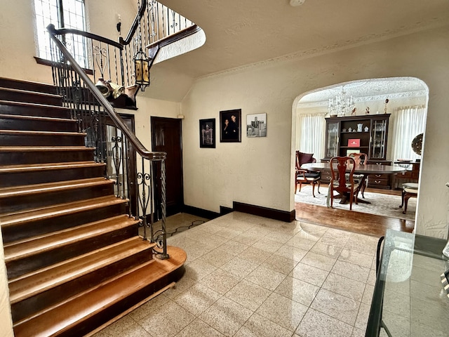 stairs featuring a textured wall, arched walkways, granite finish floor, and baseboards