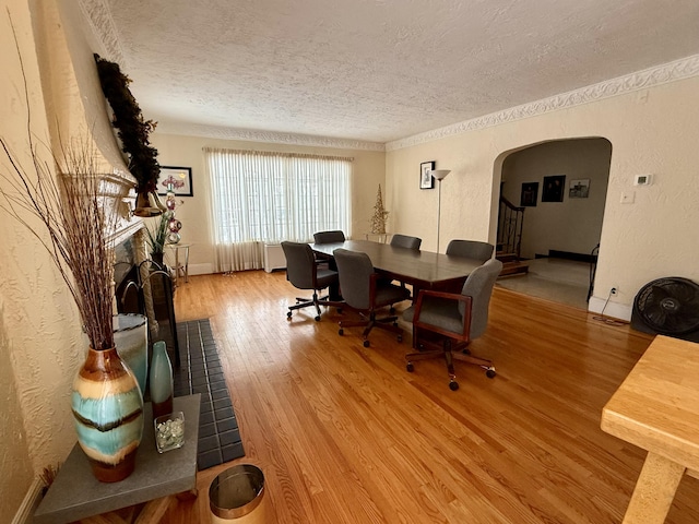 office with arched walkways, a textured wall, wood finished floors, a textured ceiling, and a fireplace