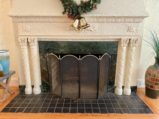 interior details featuring a textured wall, a fireplace, and wood finished floors