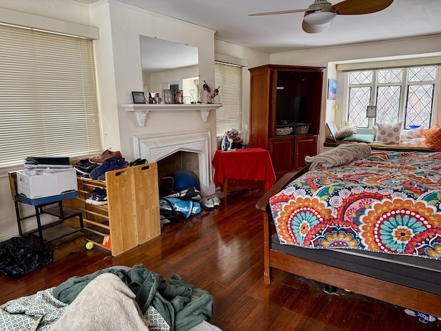 bedroom with dark wood-type flooring, a fireplace, and ceiling fan