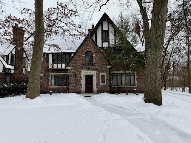 tudor home featuring brick siding and a chimney