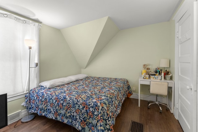 bedroom featuring dark wood-type flooring, visible vents, vaulted ceiling, and baseboards