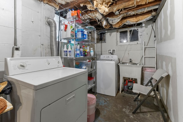 clothes washing area with laundry area, separate washer and dryer, and a sink