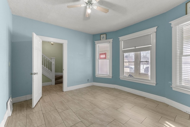 spare room with ceiling fan, stairway, and baseboards