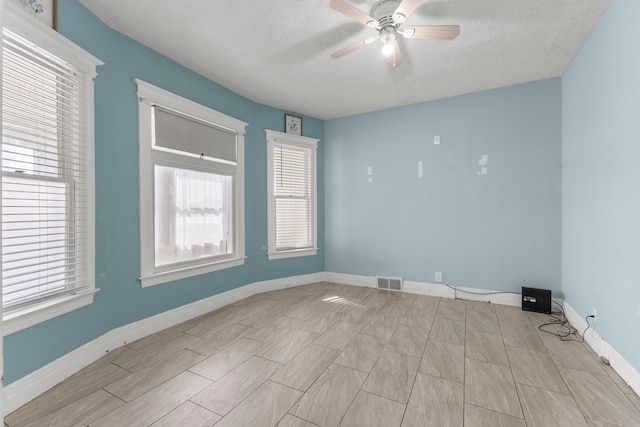 unfurnished room featuring ceiling fan, a textured ceiling, visible vents, and baseboards