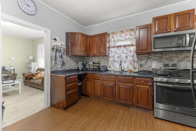 kitchen featuring dark countertops, light wood-type flooring, stainless steel appliances, and a sink