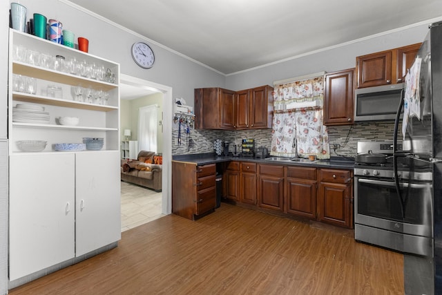 kitchen with appliances with stainless steel finishes, dark countertops, a sink, and wood finished floors