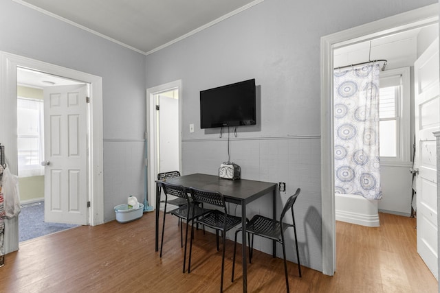 dining area with a wainscoted wall, crown molding, tile walls, and wood finished floors