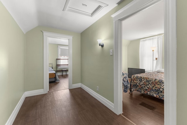 hallway with attic access, baseboards, vaulted ceiling, and dark wood-style flooring