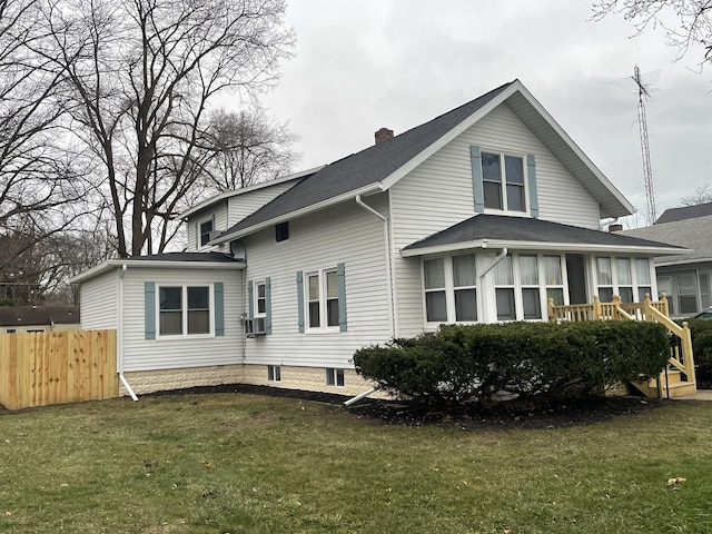 rear view of house featuring a yard, a chimney, and fence