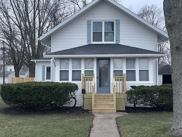 view of front facade with a front lawn and a shingled roof