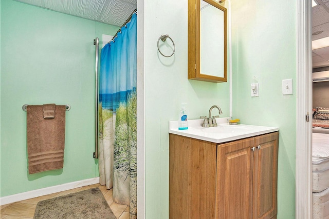 bathroom featuring curtained shower, vanity, and baseboards