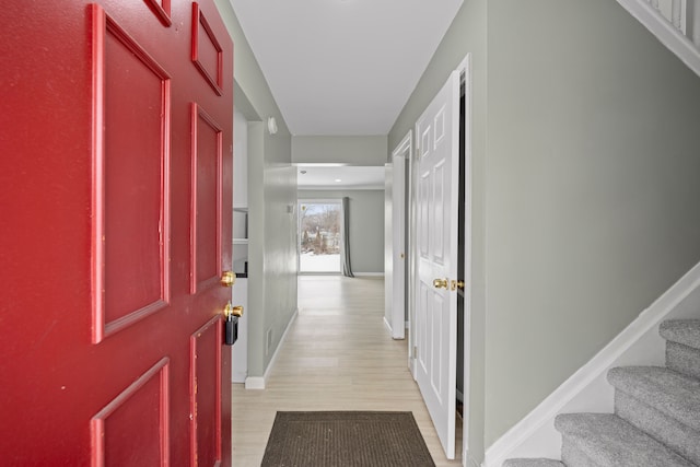 entryway with baseboards, light wood finished floors, and stairs