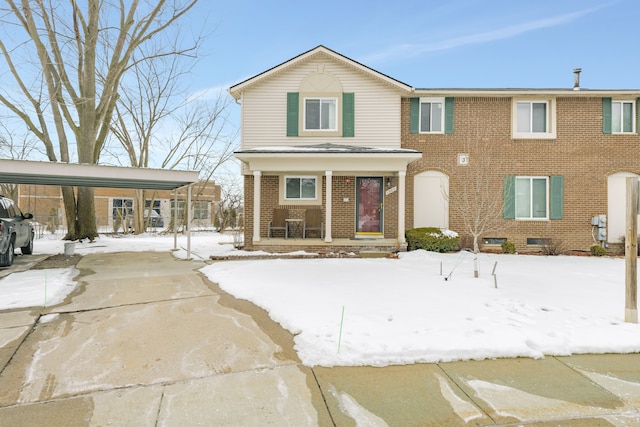 view of front of home with covered porch, a carport, brick siding, and driveway