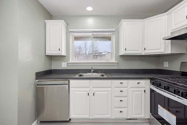 kitchen featuring appliances with stainless steel finishes, dark countertops, white cabinets, and a sink