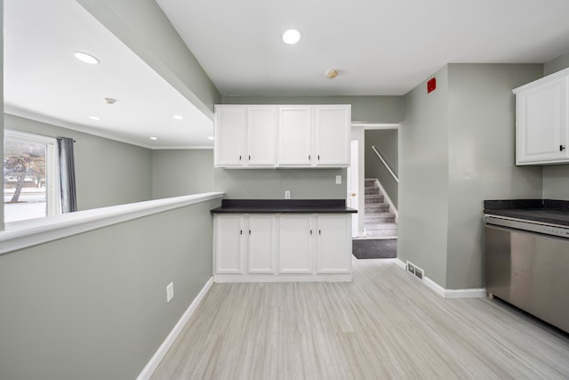 kitchen with dark countertops, white cabinetry, dishwasher, and baseboards