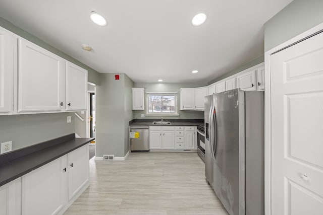 kitchen with dark countertops, white cabinetry, visible vents, and appliances with stainless steel finishes