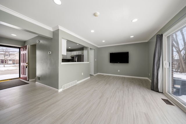 unfurnished living room with ornamental molding, visible vents, and baseboards