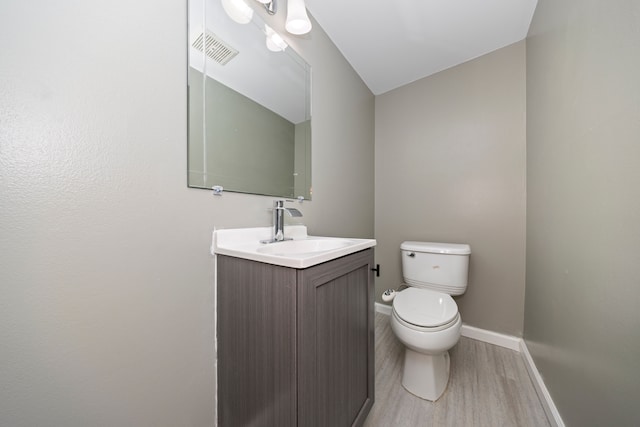 bathroom with baseboards, visible vents, toilet, wood finished floors, and vanity