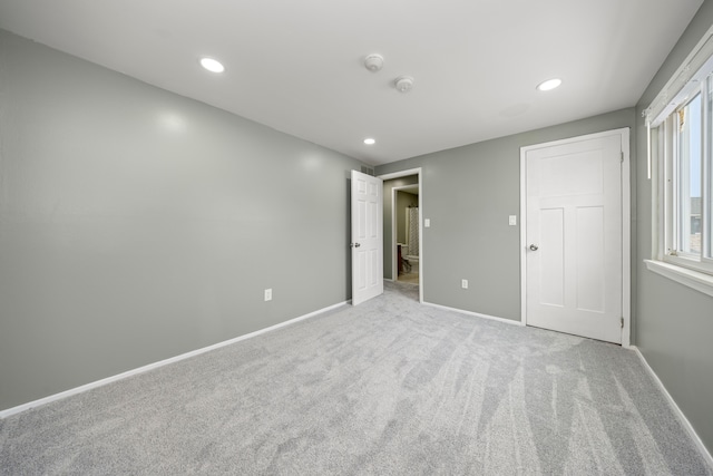 unfurnished bedroom with recessed lighting, light carpet, and baseboards