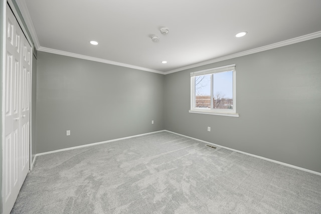 unfurnished bedroom featuring a closet, light colored carpet, crown molding, and baseboards