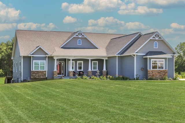 craftsman inspired home featuring stone siding, covered porch, and a front lawn