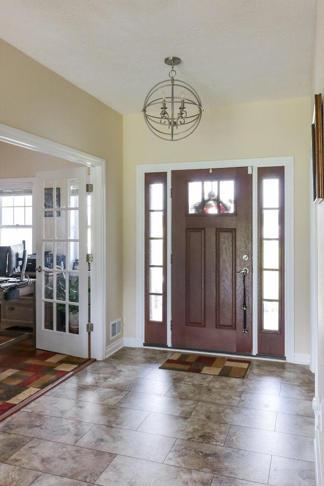 foyer with baseboards, visible vents, and an inviting chandelier