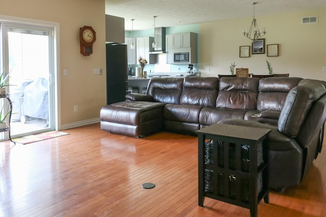 living room featuring visible vents, light wood-style flooring, baseboards, and an inviting chandelier