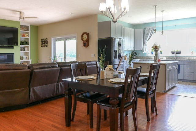 dining space with a glass covered fireplace, wood finished floors, and an inviting chandelier