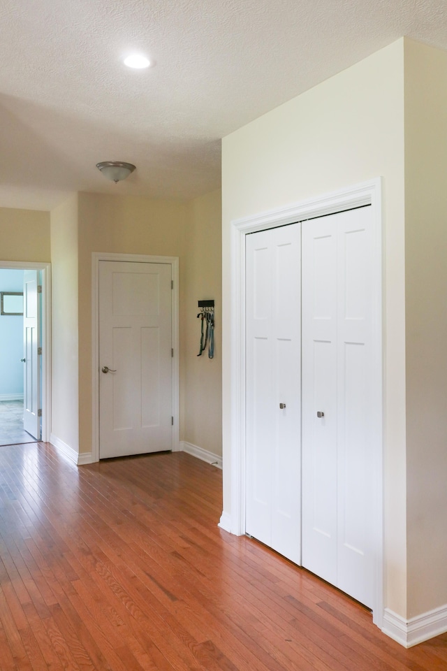 interior space featuring a textured ceiling, baseboards, and wood finished floors