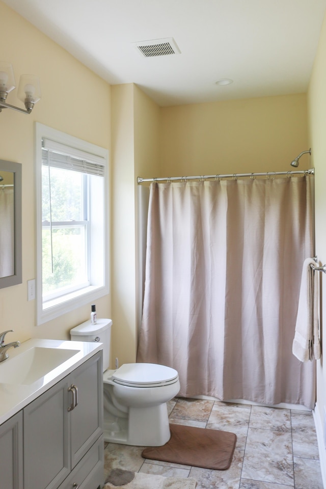 bathroom with toilet, vanity, and visible vents