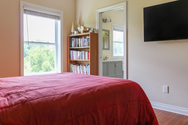 bedroom featuring baseboards, ensuite bathroom, and wood finished floors