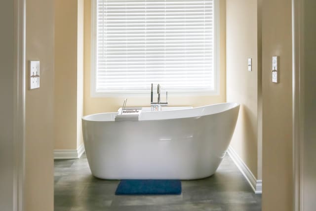 interior details with baseboards, a freestanding bath, and wood finished floors