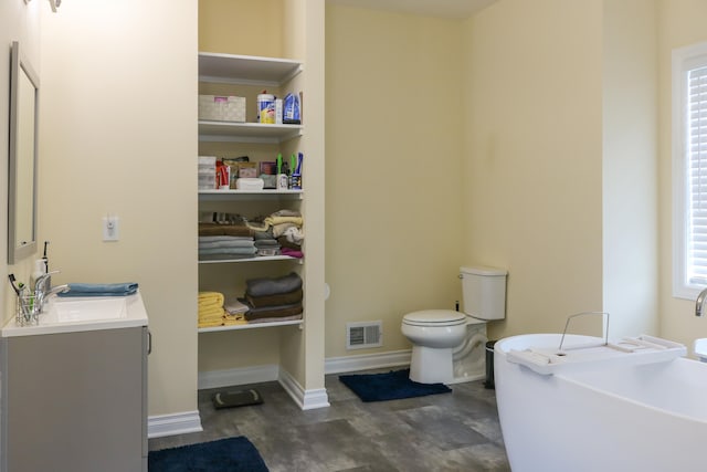 full bathroom with toilet, vanity, visible vents, baseboards, and a soaking tub