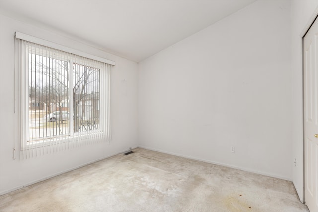 spare room featuring carpet floors, visible vents, and vaulted ceiling