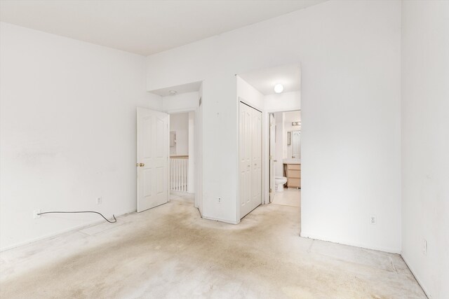 unfurnished bedroom featuring light colored carpet and connected bathroom