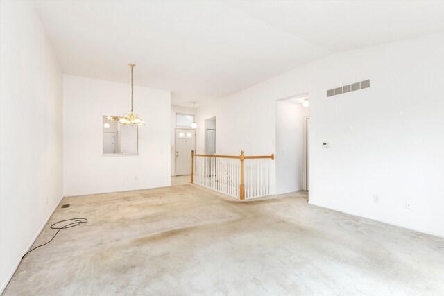 unfurnished room featuring vaulted ceiling, carpet, visible vents, and an inviting chandelier