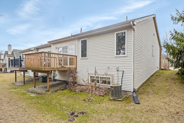 back of house with central AC unit, a deck, and a lawn