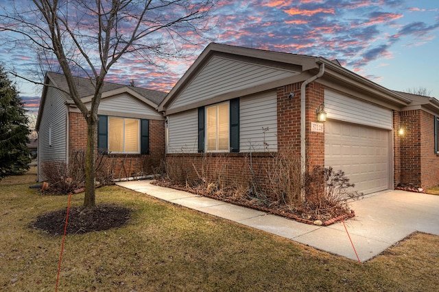 view of front of home featuring concrete driveway, brick siding, a yard, and an attached garage