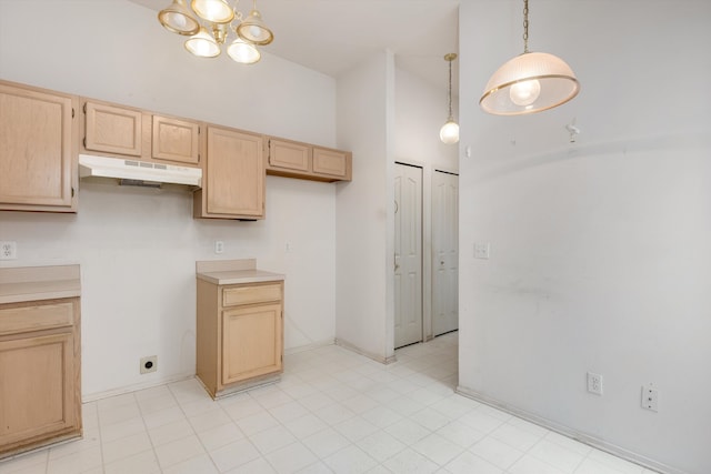 kitchen with hanging light fixtures, a high ceiling, light brown cabinetry, under cabinet range hood, and baseboards