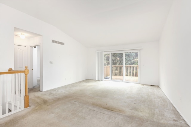 spare room with vaulted ceiling, carpet, and visible vents